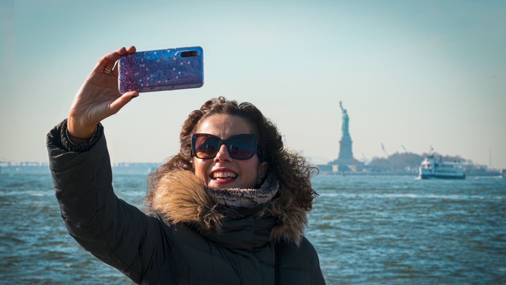 Lady taking a selfie with the Statue of Liberty